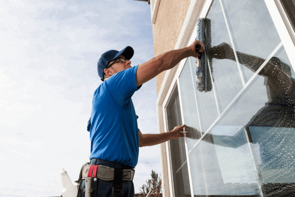 A professional window cleaner using a squeegee to clean the exterior of a building window.