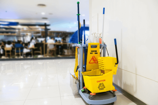 A commercial cleaning cart equipped with various cleaning tools and supplies in a public space.