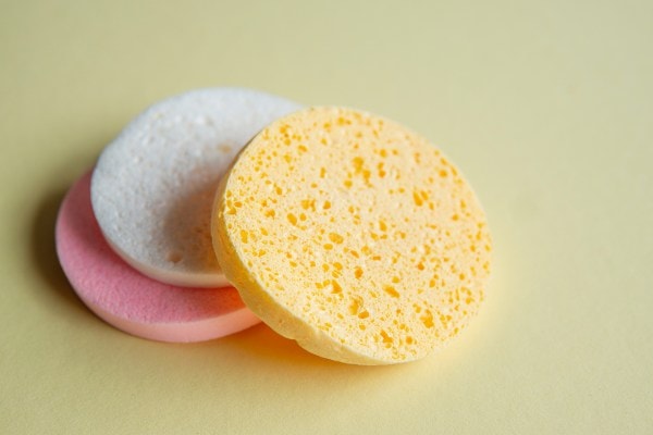 Three colorful cellulose sponges stacked on a yellow background.
