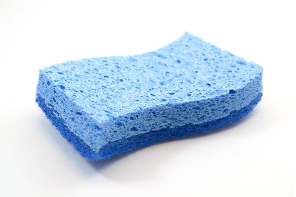 Yellow and green scrubber sponge placed on a surface.