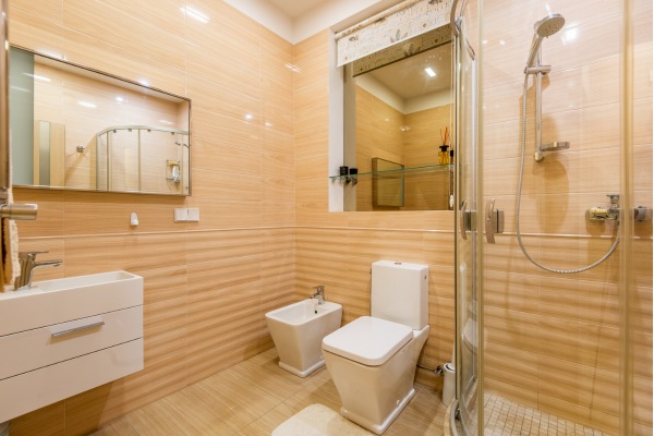 Beige bathroom with toilet, bidet, sink, and shower.