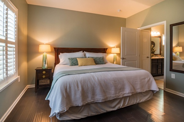 Cozy bedroom with bed, lamps, and wooden floor.