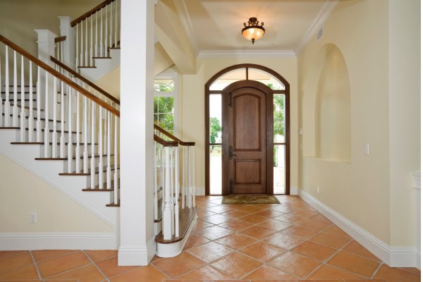 Entryway with wooden door, staircase, and tiled floor.