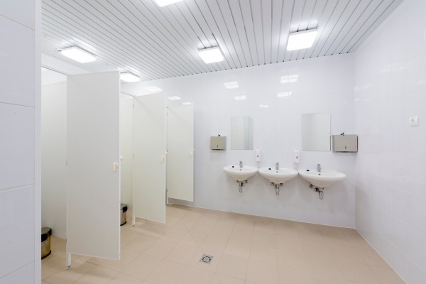 Modern bathroom with white stalls and three sinks.